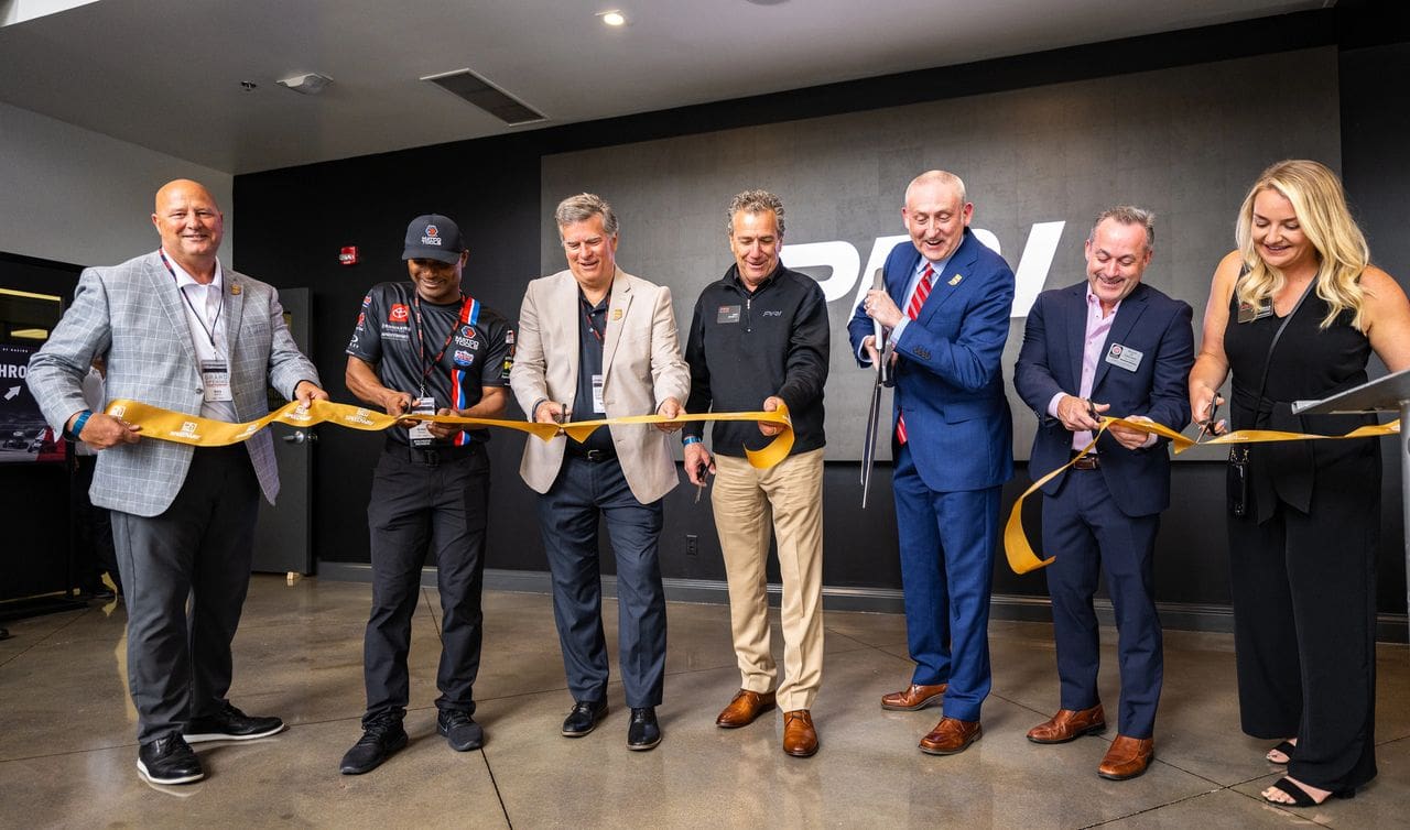 Speedway Town Council member Gary Raikes (far left) participates in a ribbon-cutting ceremony May 26 at Speedway, Ind., for the PRI Membership Headquarters. Joining him are (from left to right) NHRA Top Fuel team owner/driver Antron Brown, Speedway Town Council President Vince Noblet, SEMA CEO Mike Spagnola, PRI President Dr. Jamie Meyer, SEMA Board Chair James Lawrence, and PRI Executive Assistant Erika Stafford. (Photo courtesy of PRI)